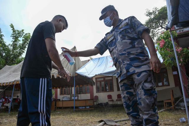 A police officer disinfects his colleague outside a morgue in Bharatpur, Chitwan on August 30, 2026, after catastrophic flooding in the Nepal-Tibet border. The number of people missing in the catastrophic flood that sliced through the border area between Nepal and Tibet neared 3,000 on August 30, as rescuers scoured deep, leg-sucking mud for survivors. (Photo by PRAKASH MATHEMA / AFP)