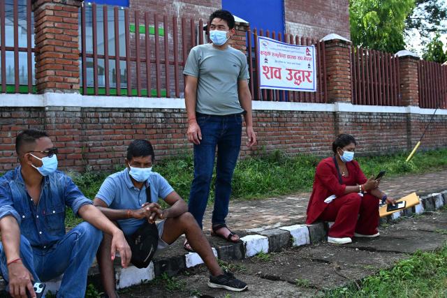 People wait to enquire about their missing relatives and family members in the aftermath of flash floods, outside a mortuary in Bharatpur of Nepal's Chitwan district on August 30, 2026. The number of people missing in the catastrophic flood that sliced through the border area between Nepal and Tibet neared 3,000 on August 30, as rescuers scoured deep, leg-sucking mud for survivors. (Photo by Prakash MATHEMA / AFP)