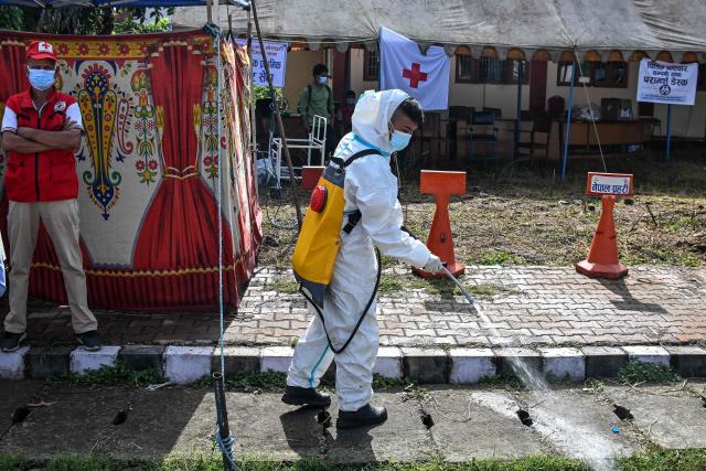 A health worker disinfects the area outside a mortuary in Bharatpur of Nepal's Chitwan district on August 30, 2026. The number of people missing in the catastrophic flood that sliced through the border area between Nepal and Tibet neared 3,000 on August 30, as rescuers scoured deep, leg-sucking mud for survivors. (Photo by PRAKASH MATHEMA / AFP)