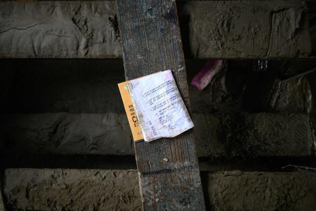 A left-behind notebook rests on a bench inside a classroom covered heavily in mud in the aftermath of flash floods at the Bageshwori secondary school in Galchi town of Nepal's Dhading district on August 30, 2026. The number of people missing in the catastrophic flood that sliced through the border area between Nepal and Tibet exceeded 3,000 on August 30, as rescuers scoured deep, leg-sucking mud for survivors. (Photo by Manan VATSYAYANA / AFP)