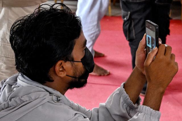 A family member takes visuals of a screen displaying identities of victims at a mortuary in the aftermath of flash floods, in Bharatpur of Nepal's Chitwan district on August 30, 2026. The number of people missing in the catastrophic flood that sliced through the border area between Nepal and Tibet neared 3,000 on August 30, as rescuers scoured deep, leg-sucking mud for survivors. (Photo by Prakash MATHEMA / AFP)