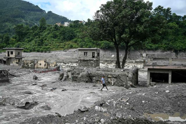 TOPSHOT - A man walks through the sludge in the aftermath of flash floods at Trishuli in Nepal's Nuwakot district on August 30, 2026. The number of people missing in the catastrophic flood that sliced through the border area between Nepal and Tibet neared 3,000 on August 30, as rescuers scoured deep, leg-sucking mud for survivors. (Photo by Arun SANKAR / AFP)
