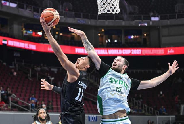 New Zealand's Flynn Cameron (L) makes a reverse lay up against Syria's David Hermes during their 2027 FIBA Basketball World Cup Asian qualifier group E match at the Mall of Asia Arena in Pasay city, Metro Manila on August 30, 2026. (Photo by Ted ALJIBE / AFP)