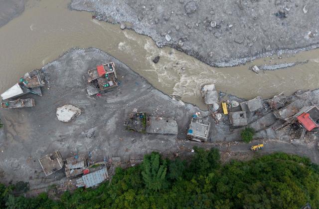An aerial view shows a torrent of muddy water surging past houses and through the Trishuli river in the aftermath of flash floods, at Betrawati in Nepal's Nuwakot district on August 29, 2026. More than 3,000 people were listed as missing on August 30, with another 768 confirmed dead, after the flash floods and landslides that hit the Nepal-Tibet border. (Photo by PRABIN RANABHAT / AFP)