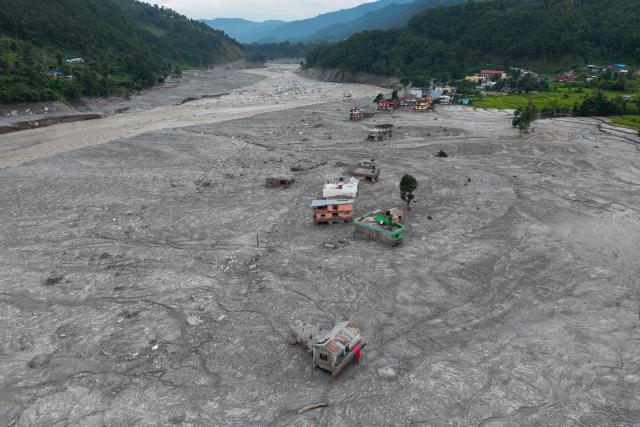 An aerial view shows houses deluged in sludge along the Trishuli river in the aftermath of flash floods at Betrawati in Nepal's Nuwakot district on August 29, 2026. More than 3,000 people were listed as missing on August 30, with another 768 confirmed dead, after the flash floods and landslides that hit the Nepal-Tibet border. (Photo by PRABIN RANABHAT / AFP)