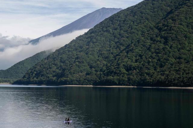 Two people ride a paddle board on lake Motosu with Mt. Fuji in the background in Minobu, Yamanashi Prefecture on August 30, 2026. (Photo by Andrew CABALLERO-REYNOLDS / AFP)