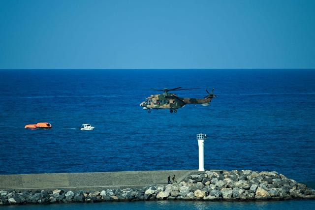 A Turkish helicopter searches the waters during a rescue operation off the coast of Kyrenia, in the self-proclaimed Turkish Republic of Northern Cyprus (TRNC), recognised only by Turkey, on August 30, 2026, after a ferry capsized. A passenger ferry capsized and sank off Northern Cyprus on August 30, killing at least seven people and leaving 23 missing, officials said, as a rescue operation was under way. The cause was not yet established. But one rescued passenger told local media a blast went off at the bow of the ferry before it rolled over. (Photo by Jewel SAMAD / AFP)