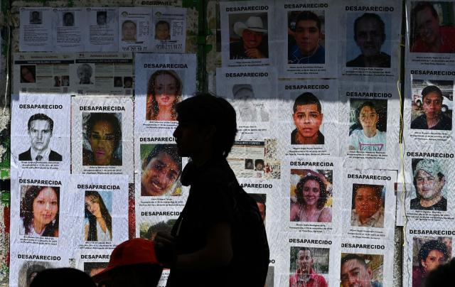 aA person walks past posters with pictures of missing people during an event to commemorate the International Day of the Victims of Enforced Disappearances at the so-called "Glorieta de las y los Desaparecidos" (Roundabout of the Disappeared) in Mexico City on August 30, 2026. (Photo by Yuri CORTEZ / AFP)