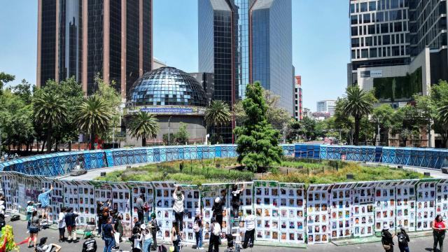 This aerial view shows members of collectives of mothers and families searching for missing persons pasting posters with pictures of their missing relatives during an event to commemorate the International Day of the Victims of Enforced Disappearances at the so-called "Glorieta de las y los Desaparecidos" (Roundabout of the Disappeared) in Mexico City on August 30, 2026. (Photo by Yuri CORTEZ / AFP)
