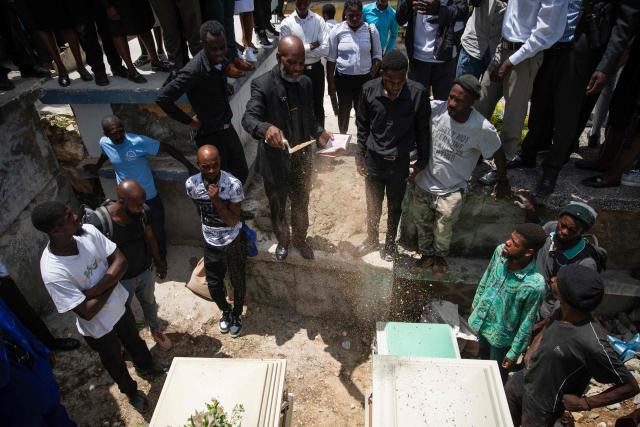 A priest throws dirt in a grave during a collective funeral for more than twenty people killed by armed gangs last week in Kenscoff, a neighborhood near Port-au-Prince, on August 30, 2026. Gang members attacked displaced people huddling inside a church near Haiti's capital, killing around 40, some of them execution-style, the mayor told AFP on August 24. (Photo by Clarens SIFFROY / AFP)