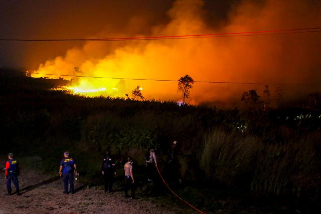 Firefighters attempt to extinguish a wildfire by spraying water and creating boundary trenches to prevent the flames from spreading in the Tumbang Nusa area of Pulang Pisau, Central Kalimantan, on August 30, 2026. Indonesia has intensified efforts to fight wildfires with cloud seeding and water bombing as thousands of people countrywide battle to breathe in the smoke and haze, officials said on August 28. More than five million people on Borneo and Sumatra islands were directly exposed to the risks of a putrid haze coming off dozens of fires across the vast archipelago, according to deputy health minister Dante Saksono Harbuwono. (Photo by REINA / AFP)