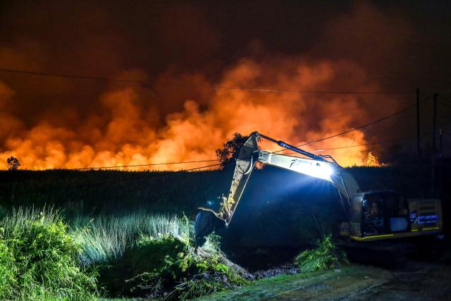 An excavator digs a trench in an attempt to extinguish a wildfire by spraying water and creating boundary trenches to prevent the flames from spreading in the Tumbang Nusa area of Pulang Pisau, Central Kalimantan, on August 30, 2026. Indonesia has intensified efforts to fight wildfires with cloud seeding and water bombing as thousands of people countrywide battle to breathe in the smoke and haze, officials said on August 28. More than five million people on Borneo and Sumatra islands were directly exposed to the risks of a putrid haze coming off dozens of fires across the vast archipelago, according to deputy health minister Dante Saksono Harbuwono. (Photo by REINA / AFP)
