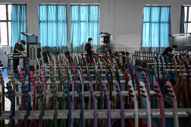 This photo taken on July 27, 2026 shows employees working on a guitar production line at a factory of Natasha guitar company in Zheng'an, in southwestern China's Guizhou Province. The town of Zheng'an in the southwest province of Guizhou produces one in every seven of the instruments sold worldwide -- but a decade ago, it had no guitar-making industry to speak of at all. (Photo by Jade GAO / AFP) / To go with AFP story 'China-Economy-Trade-Manufacturing-Music', Reportage by Rita QIAN