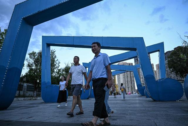 This photo taken on July 26, 2026 shows people walking past installations of musical notes at the Guitar Cultural Plaza in Zheng'an, in southwestern China's Guizhou Province. The town of Zheng'an in the southwest province of Guizhou produces one in every seven of the instruments sold worldwide -- but a decade ago, it had no guitar-making industry to speak of at all. (Photo by Jade GAO / AFP) / To go with AFP story 'China-Economy-Trade-Manufacturing-Music', Reportage by Rita QIAN