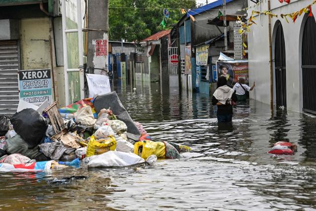 People wade through a flooded street after heavy rains brought by the southwest monsoon in Pampanga on August 31, 2026. (Photo by Jam STA ROSA / AFP)