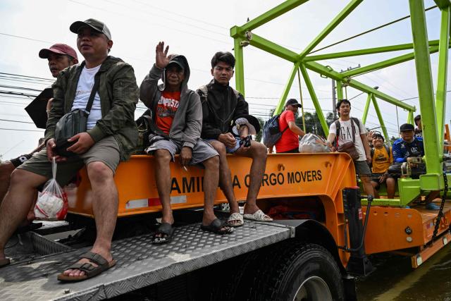 People ride on a truck as it moves through a flooded street after heavy rains brought by the southwest monsoon in Pampanga on August 31, 2026. (Photo by Jam STA ROSA / AFP)