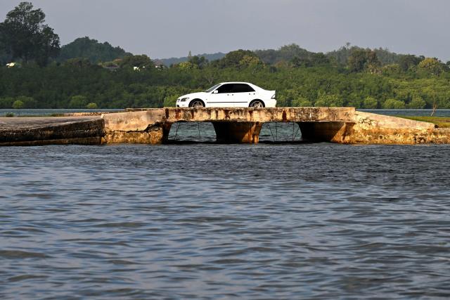 A car crosses a low-lying bridge during high tide at sunrise in Koror, Palau, on August 31, 2026. (Photo by SAEED KHAN / AFP)