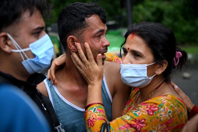 People mourn their missing relatives in the aftermath of flash floods, outside a mortuary in Nepal's Chitwan district on August 31, 2026. Nepal was burying on August 31 some of the hundreds of bodies retrieved after a deadly, tsunami-like flood crashed through the Himalayan region, sweeping away villages and leaving thousands still missing. Distraught families have packed rescue stations and hospitals in search of their missing relatives, while others have faced the grim task of identifying bodies at overflowing morgues. (Photo by Prakash MATHEMA / AFP)