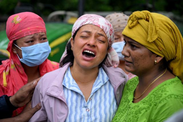 People mourn their missing relatives in the aftermath of flash floods, outside a mortuary in Nepal's Chitwan district on August 31, 2026. Nepal was burying on August 31 some of the hundreds of bodies retrieved after a deadly, tsunami-like flood crashed through the Himalayan region, sweeping away villages and leaving thousands still missing. Distraught families have packed rescue stations and hospitals in search of their missing relatives, while others have faced the grim task of identifying bodies at overflowing morgues. (Photo by Prakash MATHEMA / AFP)