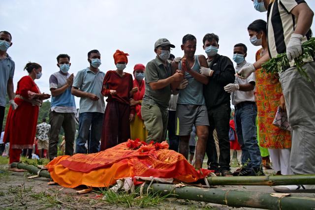 Ayush Khadka's father Krishna Khadka (5R) mourns during his son's cremation in the aftermath of flash floods, in Nepal's Chitwan district on August 31, 2026. Nepal was burying on August 31 some of the hundreds of bodies retrieved after a deadly, tsunami-like flood crashed through the Himalayan region, sweeping away villages and leaving thousands still missing. Distraught families have packed rescue stations and hospitals in search of their missing relatives, while others have faced the grim task of identifying bodies at overflowing morgues. (Photo by Prakash MATHEMA / AFP)