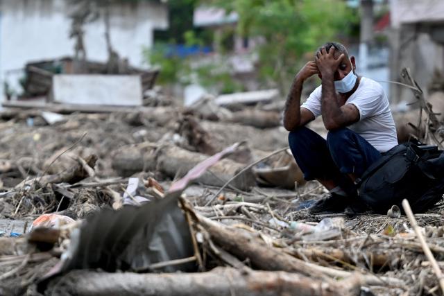 A man sits beside debris as he salvages belongings following flash floods at Devighat in Nepal's Nuwakot district on August 31, 2026. Nepal was burying on August 31 some of the hundreds of bodies retrieved after a deadly, tsunami-like flood crashed through the Himalayan region, sweeping away villages and leaving thousands still missing. Distraught families have packed rescue stations and hospitals in search of their missing relatives, while others have faced the grim task of identifying bodies at overflowing morgues. (Photo by Arun SANKAR / AFP)