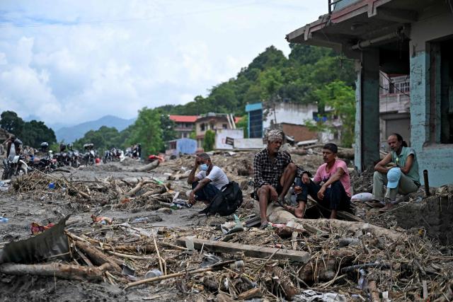 TOPSHOT - Residents sit beside debris as they salvage belongings following flash floods at Devighat in Nepal's Nuwakot district on August 31, 2026. Nepal was burying on August 31 some of the hundreds of bodies retrieved after a deadly, tsunami-like flood crashed through the Himalayan region, sweeping away villages and leaving thousands still missing. Distraught families have packed rescue stations and hospitals in search of their missing relatives, while others have faced the grim task of identifying bodies at overflowing morgues. (Photo by Arun SANKAR / AFP)