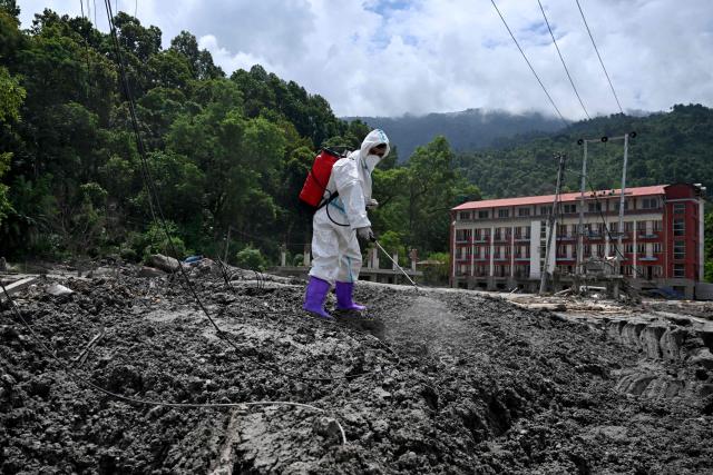 A health worker sprays disinfectant following flash floods at Devighat in Nepal's Nuwakot district on August 31, 2026. Nepal was burying on August 31 some of the hundreds of bodies retrieved after a deadly, tsunami-like flood crashed through the Himalayan region, sweeping away villages and leaving thousands still missing. Distraught families have packed rescue stations and hospitals in search of their missing relatives, while others have faced the grim task of identifying bodies at overflowing morgues. (Photo by Arun SANKAR / AFP)