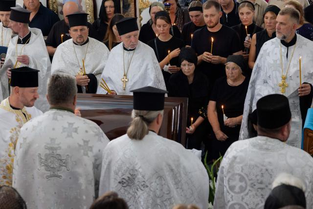 Clergymen stand around the coffin of Taras Didych, head of the Dmytrivka community, who was killed in a Russian attack that killed 37 people on August 29, during his funeral in Dmytrivka, Kyiv region, on August 31, 2026, amid Russia’s invasion of Ukraine. (Photo by Tetiana DZHAFAROVA / AFP)
