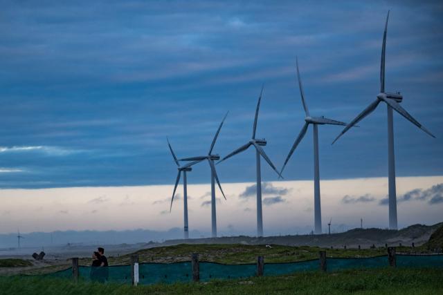 People walk at Nikkawahama Beach as wind turbines are seen in background in Kamisu city, Ibaraki prefecture on August 31, 2026. (Photo by Philip FONG / AFP)