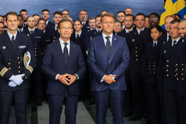 French President Emmanuel Macron (C-R) and Swedish Prime Minister Ulf Kristersson (C-L) pose for a group picture with crew members aboard the French frigate Amiral Ronarc’h in Stockholm, Sweden, on August 31, 2026, following the signing of a 4.3-billion-euro contract for Sweden’s acquisition of four French-built defence and intervention frigates (FDI). (Photo by Ludovic MARIN / AFP)
