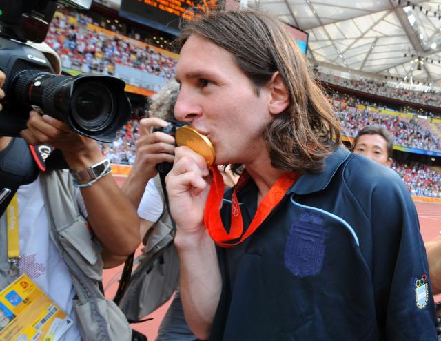 (FILES) Argentinian forward Lionel Messi kisses his gold medal as he leaves the pitch after attending the men's Olympic football tournament medal ceremony at the national stadium in Beijing during the 2008 Beijing Olympic games on August 23, 2008. Argentina won gold ahead of Nigeria and Brazil. Argentine football player Lionel Messi said on August 31, 2026, he is retiring from international football after leading Argentina to a second successive World Cup final. (Photo by JEWEL SAMAD / AFP)