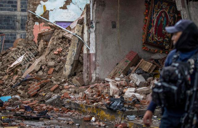 A State Police officer walks amid remains caused by a car bomb explosion outside the municipal police station in Ojocaliente, Zacatecas, Mexico, on August 31, 2026. A car bomb exploded on August 30 night in front of a police station in Mexico, wounding six people, authorities said. The attack took place in the state of Zacatecas, which has key routes for drug trafficking. (Photo by Jess Mireles / AFP)