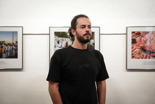 French-Syrian photographer Abdulmonam Eassa poses next his displayed photographs during a photo session during the 38th edition of the "Visa pour l'image" press photography festival in Perpignan, southwestern France, on August 31, 2026. (Photo by Valentine CHAPUIS / AFP)