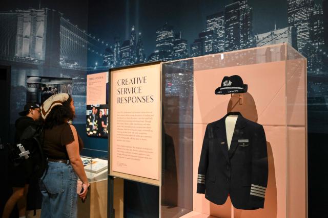 Members of the media view an exhibit at a press preview of the 9/11 Memorial & Museum’s exhibition, “In Their Honor: 25 Years of 9/11 Inspired Service”, exploring the legacy of service inspired by September 11, 2001, in New York, on August 31, 2026. September 11, 2026 will mark the 25th anniversary of the September 11, 2001 attacks. (Photo by ANGELA WEISS / AFP)