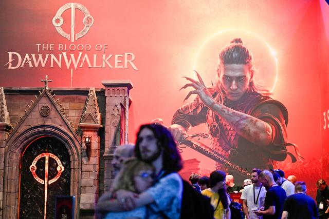 (FILES) Gamers stand at the booth of The Blood of Dawnwalker video game of Rebel Wolves at the Gamescom video games trade fair on the fair grounds in Cologne, western Germany, on August 26, 2026. Former members of “The Witcher 3” team are launching their own saga with “The Blood of Dawnwalker”. (Photo by Ina FASSBENDER / AFP)