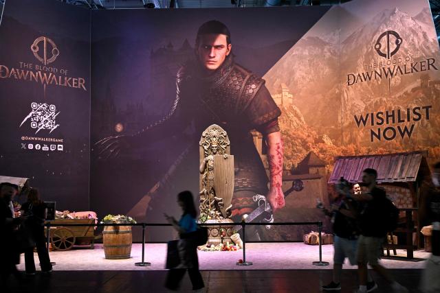 (FILES) Visitors walk past The Blood of Dawnwalker video game booth during the Gamescom video games trade fair at the Trade Fair Center in Cologne, western Germany, on the first day of the fair on August 20, 2025. Former members of “The Witcher 3” team are launching their own saga with “The Blood of Dawnwalker”. (Photo by Ina FASSBENDER / AFP)