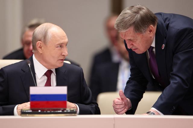 In this pool photograph distributed by the Russian state agency Sputnik, Russia's President Vladimir Putin and foreign policy presidential aide Yuri Ushakov interact prior to the Shanghai Cooperation Organisation (SCO) summit in Bishkek on September 1, 2026. (Photo by Peter KOVALEV / POOL / AFP)