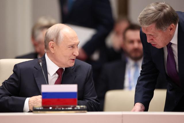 In this pool photograph distributed by the Russian state agency Sputnik, Russia's President Vladimir Putin and foreign policy presidential aide Yuri Ushakov interact prior to the Shanghai Cooperation Organisation (SCO) summit in Bishkek on September 1, 2026. (Photo by Peter KOVALEV / POOL / AFP)