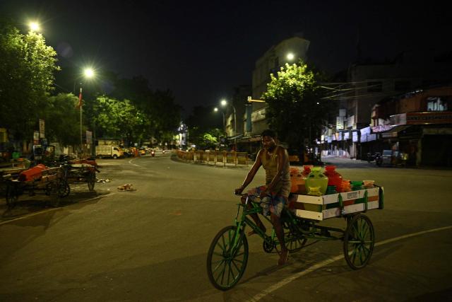 A man rides his tricycle carrying water pots along a road, at dawn in Chennai on September 1, 2026. (Photo by R.Satish BABU / AFP)