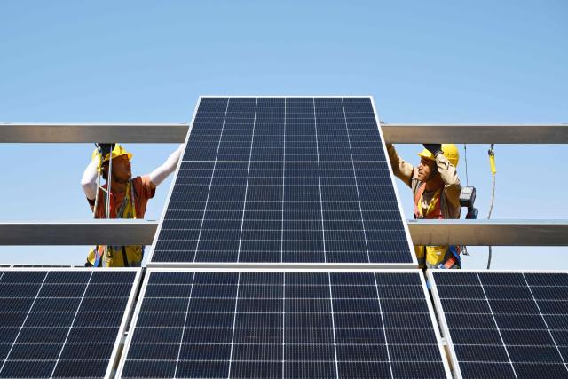 (FILES) Workers install solar panels at the Ningguoyun Lingwu 1 million kilowatt photovoltaic project in the desert at Lingwu, in China’s northern Ningxia region on April 14, 2025. China's installed solar energy capacity has surpassed that of coal-fired power for the first time, the national energy body said on September 1, 2026, hailing the milestone. (Photo by CN-STR / AFP) / China OUT