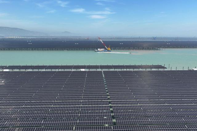 (FILES) Workers install solar panels with a crane at the CNNC Tianwan tidal flat photovoltaic power plant in Lianyungang, in China's eastern Jiangsu province, on April 19, 2026. China's installed solar energy capacity has surpassed that of coal-fired power for the first time, the national energy body said on September 1, 2026, hailing the milestone. (Photo by CN-STR / AFP) / China OUT