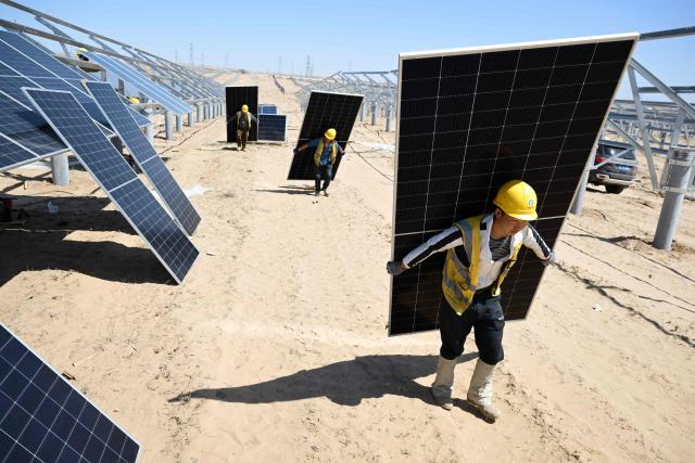 (FILES) Workers carry solar panels to be installed in the desert at the Ningguoyun Lingwu 1 million kilowatt photovoltaic project in Lingwu, in China’s northern Ningxia region on April 14, 2025. China's installed solar energy capacity has surpassed that of coal-fired power for the first time, the national energy body said on September 1, 2026, hailing the milestone. (Photo by CN-STR / AFP) / China OUT