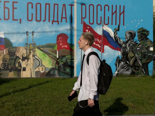 A teenager walks past a graffiti piece dedicated to the Russian military action in Ukraine on the first day of the school year in Moscow on September 1, 2026. (Photo by Andrey BORODULIN / AFP)
