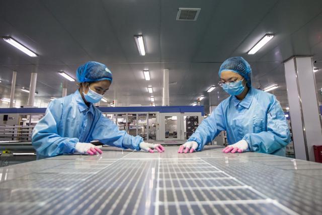 (FILES) Employees work on solar photovoltaic modules at a factory in Haian in China's eastern Jiangsu province on November 15, 2021. China's installed solar energy capacity has surpassed that of coal-fired power for the first time, the national energy body said on September 1, 2026, hailing the milestone. (Photo by CN-STR / AFP) / China OUT