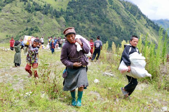 Flood affected people receive relief supplies from Nepal Armed Police Force personnel in Nepal's Rasuwa district on September 1, 2026. The huge wave of freezing water and debris, sparked by a glacial collapse on the China-Nepal border, killed at least 939 people and left nearly 4,500 missing, with Kathmandu warning reconstruction costs could run into the "billions of dollars". (Photo by Prabin RANABHAT / AFP)