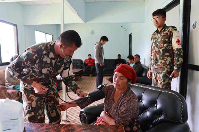 A Nepal Army personnel checks the blood pressure of a flood affected villager in Nepal's Rasuwa district on September 1, 2026. The huge wave of freezing water and debris, sparked by a glacial collapse on the China-Nepal border, killed at least 939 people and left nearly 4,500 missing, with Kathmandu warning reconstruction costs could run into the "billions of dollars". (Photo by PRABIN RANABHAT / AFP)