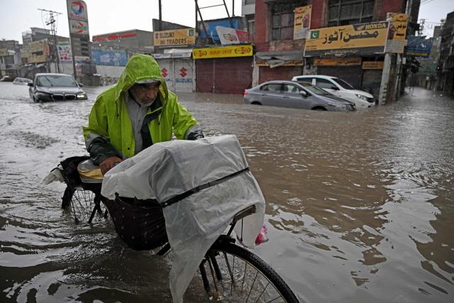 Commuters wade through a flooded street after heavy monsoon rainfall in Rawalpindi on September 1, 2026. (Photo by Aamir QURESHI / AFP)