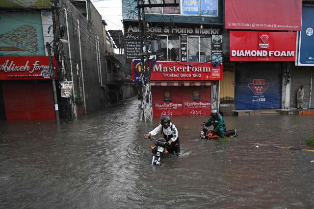 Commuters wade through a flooded street after heavy monsoon rainfall in Rawalpindi on September 1, 2026. (Photo by Aamir QURESHI / AFP)