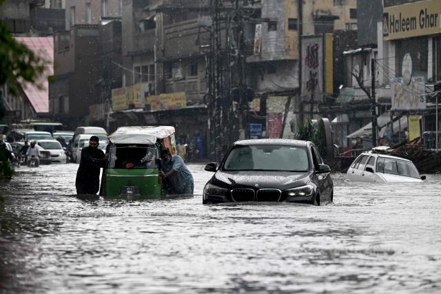 Commuters wade through a flooded street after heavy monsoon rainfall in Rawalpindi on September 1, 2026. (Photo by Aamir QURESHI / AFP)