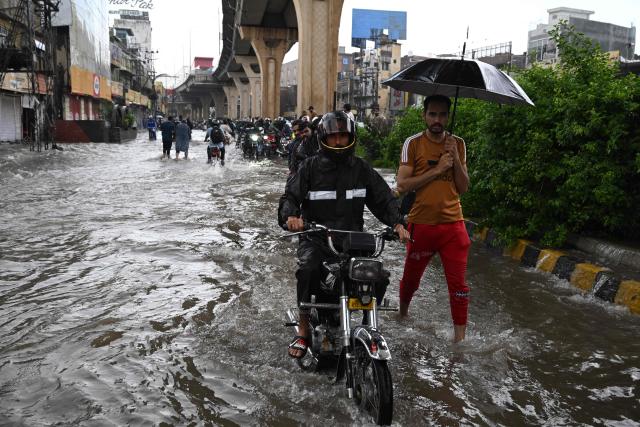Commuters wade through a flooded street after heavy monsoon rainfall in Rawalpindi on September 1, 2026. (Photo by Aamir QURESHI / AFP)